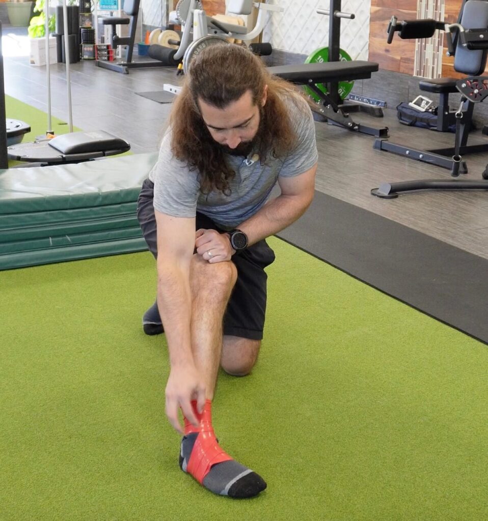 Dr. John demonstraing plantar flexion with a muscle floss band on